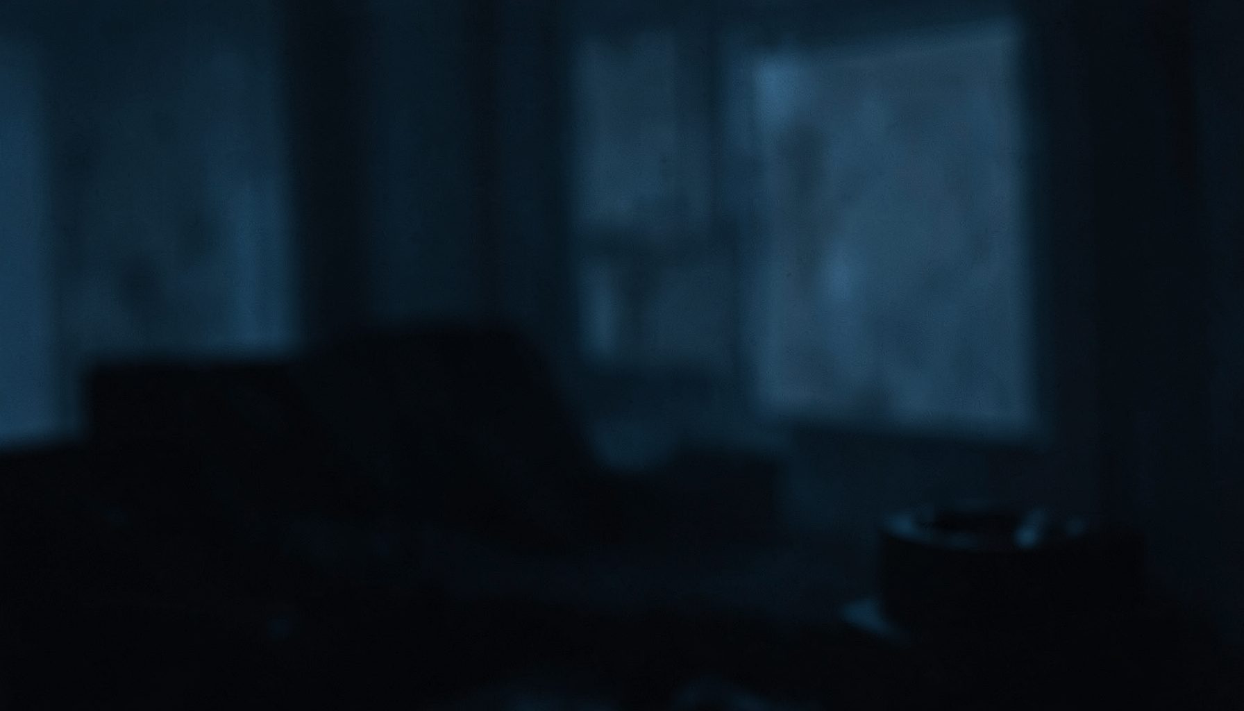 A dimly lit, atmospheric scene with deep blue and muted gray tones, suggesting quiet introspection and the internal weight of worry