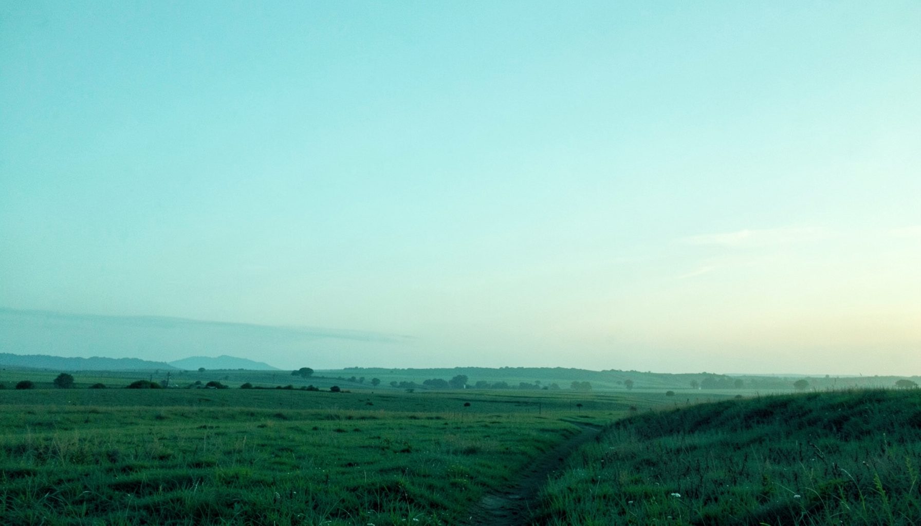 A wide, serene landscape at dawn with soft teal and pale blue tones, open sky, and a gentle horizon suggesting hope and new beginnings.