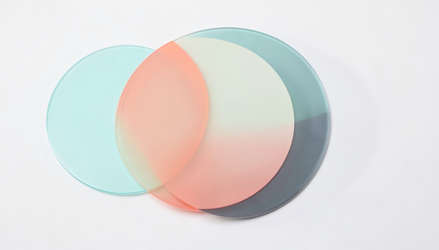 Three translucent overlapping circles in soft teal, coral, and slate, representing interconnected layers of experience